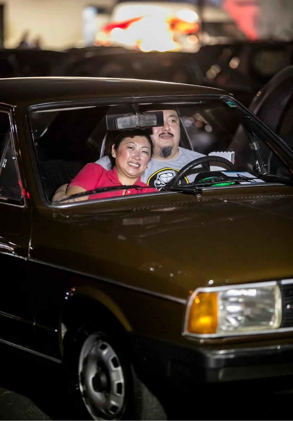 Casal abraçado dentro de um carro clássico marrom durante a sessão